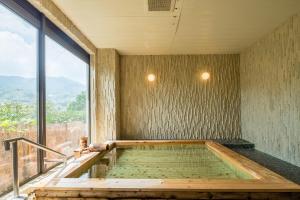 uma banheira de hidromassagem num quarto com uma grande janela em Apolosou em Yugawara
