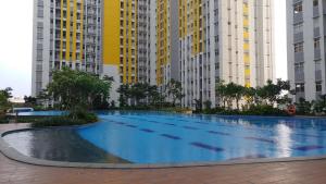 a large swimming pool in a city with tall buildings at Modern and Full Parquette Studio Springlake Summarecon Bekasi Apartment By Travelio in Bekasi