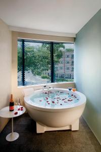 eine große weiße Badewanne in einem Zimmer mit Fenster in der Unterkunft D'Hotel Singapore managed by The Ascott Limited in Singapur