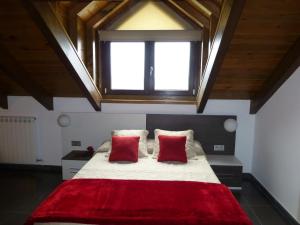 a bedroom with a large bed with two red pillows at La Solana de Jaca - Casa Collarada in Novés
