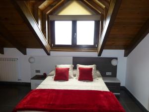 um quarto com uma cama grande e 2 almofadas vermelhas em La Solana de Jaca - Casa Collarada em Novés