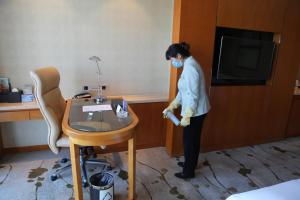 a woman in a hotel room with a mask and a table at Yiwu Shangcheng Hotel in Yiwu