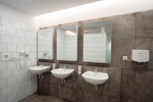a bathroom with two sinks and two mirrors at Bobopod Kota Tua, Jakarta in Jakarta