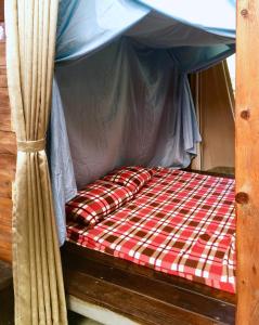 a canopy bed with a red and white plaid at Shuitianfarm in Jianshi