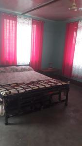 a bedroom with a bed with pink curtains and windows at Pandeys Homestay Kalimpong in Kalimpong