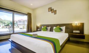 a bedroom with a large bed and a large window at Treebo Trend JP Cottage in Mahabaleshwar