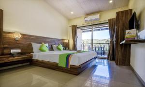 a bedroom with a large bed and a balcony at Treebo Trend JP Cottage in Mahabaleshwar