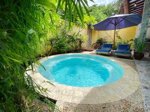 una pequeña piscina con 2 sillas azules y una sombrilla en Cinta Cottages, en Gili Trawangan