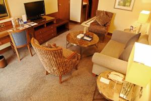 a living room with a couch and chairs and a television at Golden Tulip Bahrain in Manama