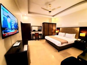 a hotel room with a bed and a flat screen tv at Magnolia Boutique House in Islamabad