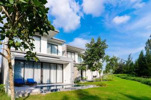 a white house with blue chairs in the yard at Clean & Quiet Villa - The Point Resort in Danang
