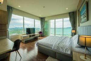a bedroom with a bed and a tv and windows at Movenpick Residences Pattaya with Ocean View in Na Jomtien