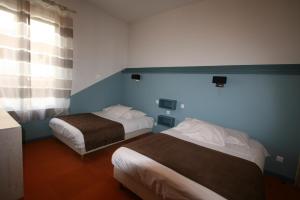 ein Hotelzimmer mit zwei Betten und einem Fenster in der Unterkunft Hôtel Le Picardy in Saint-Dizier