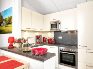 - une cuisine avec des placards blancs et un bol rouge sur un comptoir dans l'établissement Dänische Ferienhäuser am Salzhaff Haus Vogelparadies, à Poel