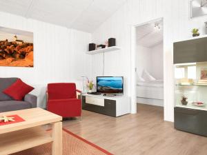 - un salon avec une télévision et une chaise rouge dans l'établissement Dänische Ferienhäuser am Salzhaff Haus Vogelparadies, à Poel