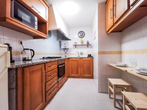 a large kitchen with wooden cabinets and a microwave at Casa Poema Next To River Tejo & Zêzere in Constância