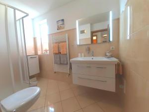 ein Badezimmer mit einem Waschbecken, einem WC und einem Spiegel in der Unterkunft Ferienwohnungen Auf der Düne in Cuxhaven