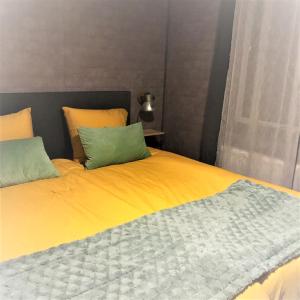 a yellow bed with two green pillows on it at Luxe All season Chalet De Goudenregen in Balkbrug