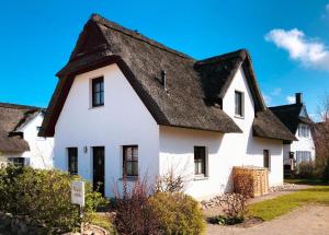 een wit huis met een zwart dak bij Reetdachhaus Hus Kieker in Insel Poel