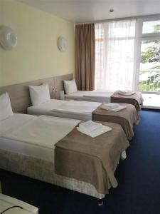 a hotel room with three beds and a window at Курортный отель Coocoorooza in Sochi