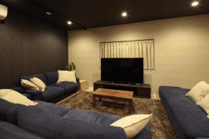 sala de estar con sofás azules y TV de pantalla plana en 照宿 Terasu yado, en Aira