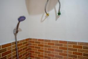 a shower in a bathroom with a brick wall at RedDoorz Syariah near GOR Satria 4 in Sumbang