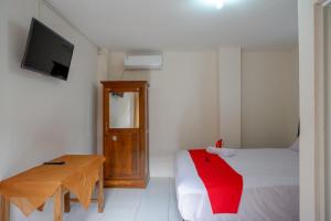 a room with a bed and a table and a television at RedDoorz Syariah near GOR Satria 4 in Sumbang