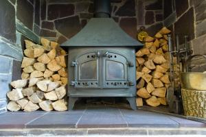 an outdoor stove with a pile of logs at Tyn Rhos Country House in Caernarfon