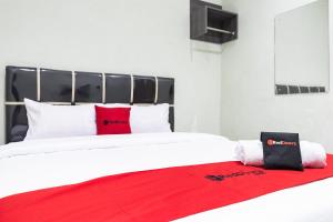 a bedroom with two beds with a red blanket at RedDoorz near Medan Amplas in Delitua