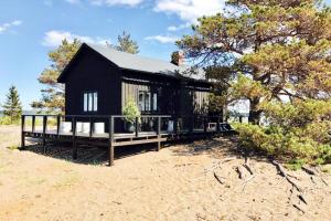 a black house with a porch on a beach at H A R R B Å D A - kaksi mökkiä merenrannalla in Kokkola