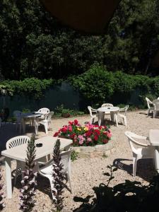 - un ensemble de tables et de chaises dans un jardin fleuri dans l'établissement Hotel Il Parco Sirolo, à Sirolo