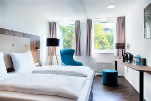 a hotel room with two beds and a blue chair at ACHAT Hotel Stuttgart Zuffenhausen in Stuttgart