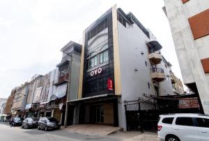 a building on a street with cars parked in front of it at Super OYO 3159 Festive Inn in Medan