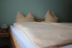 a bed with white sheets and pillows on it at Ferienwohnungen Grüne Tanne in Thale