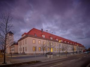 a large white building with a red roof on a street at Apartment:house Klosterbau in Neutraubling