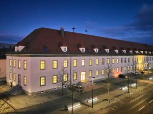 ein großes weißes Gebäude mit rotem Dach in der Nacht in der Unterkunft Apartment:house Klosterbau in Neutraubling