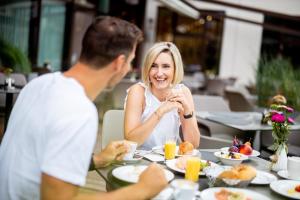 Ein Mann und eine Frau sitzen am Tisch und essen Essen. in der Unterkunft Seepark Wörthersee Resort in Klagenfurt am Wörthersee