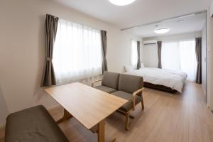 a bedroom with a bed and a table and a bed and window at Beans Stay Ishibiki in Kanazawa