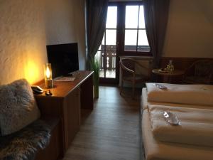 een hotelkamer met een bank en een bureau met een televisie bij See-Hotel Storchenmuehle in Fichtenau