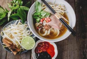 a bowl of soup with noodles and other food on a table at Mira Hotel Quy Nhơn in Quy Nhon