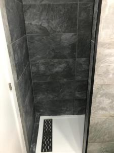 een badkamer met een douche en een zwart betegelde muur bij Casita tranquila in Talavera de la Reina