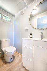 W łazience znajduje się biała toaleta i lustro. w obiekcie Cosy cabin to stay even better than Glamping w mieście Pukekohe East