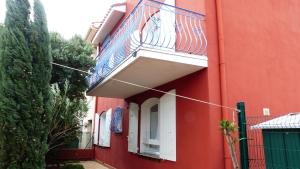 a red building with a balcony on the side of it at Appartement Stade Aime Giral in Perpignan