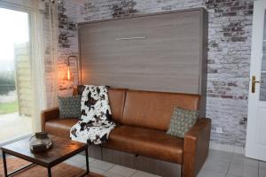 a brown couch in a room with a brick wall at Ces jours en baie Le vue mer in Cayeux-sur-Mer