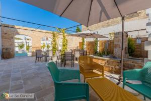 patio con sedie, tavoli e ombrellone di Le Sei Conche Relais & SPA a Gemini
