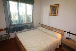 una piccola camera con letto e finestra di Villetta Sonia a Lignano Sabbiadoro