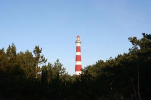 un phare rouge et blanc assis au sommet d'une colline dans l'établissement Amelander Kaap 109, à Hollum