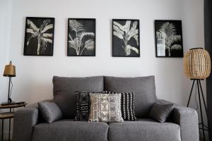 un sofá gris en una sala de estar con 4 cuadros en la pared en Calma Suites, en Sevilla