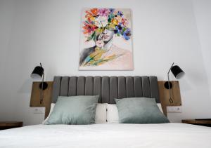 1 dormitorio con 1 cama con una pintura en la pared en Calma Suites, en Sevilla