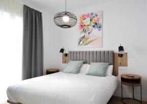 Un dormitorio con una cama blanca y una pintura en la pared en Calma Suites, en Sevilla